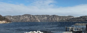 A lake with mountains in the background, a dock, and a wooden pier. - Newfoundland's Wilderness Called.   It has Starlink and a Hot Tub now. (Hermitage)
