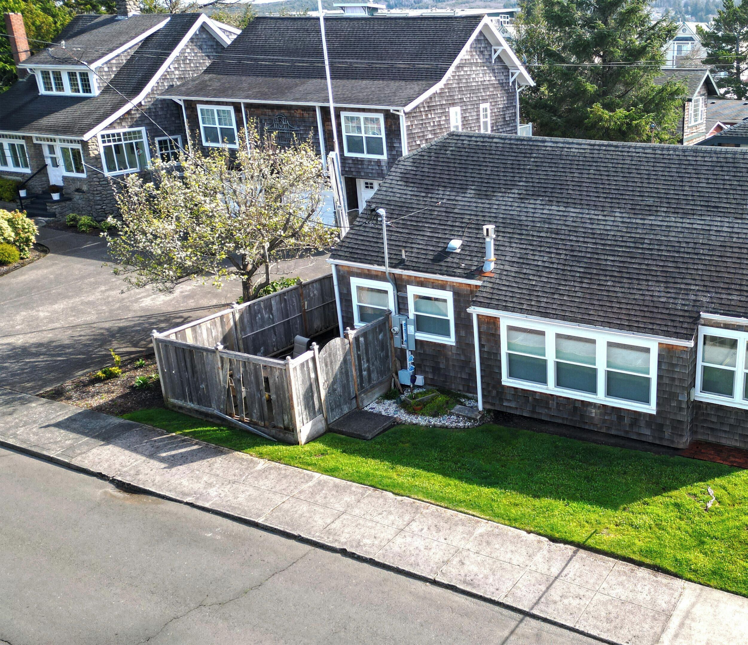 A residential house with a sloped roof, a fenced yard, and a clear driveway.