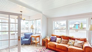 A room with a leather sofa, a blue chair, a wooden table, and a lamp. - Cozy Cottage at Seaside Beach (Seaside)