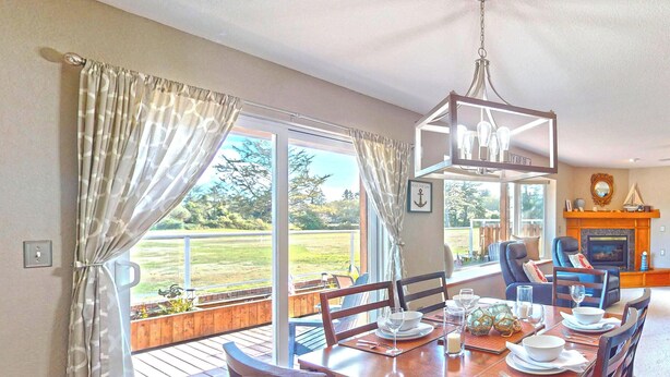 Uma sala de jantar com uma mesa posta para quatro pessoas, janelas amplas e uma lareira.