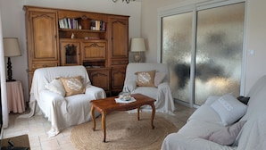 A living room with two white sofas, a wooden coffee table, a large wooden bookcase, and a chandelier. - Family home in Parc-Vallière neighborhood, near Royan beach (Royan)