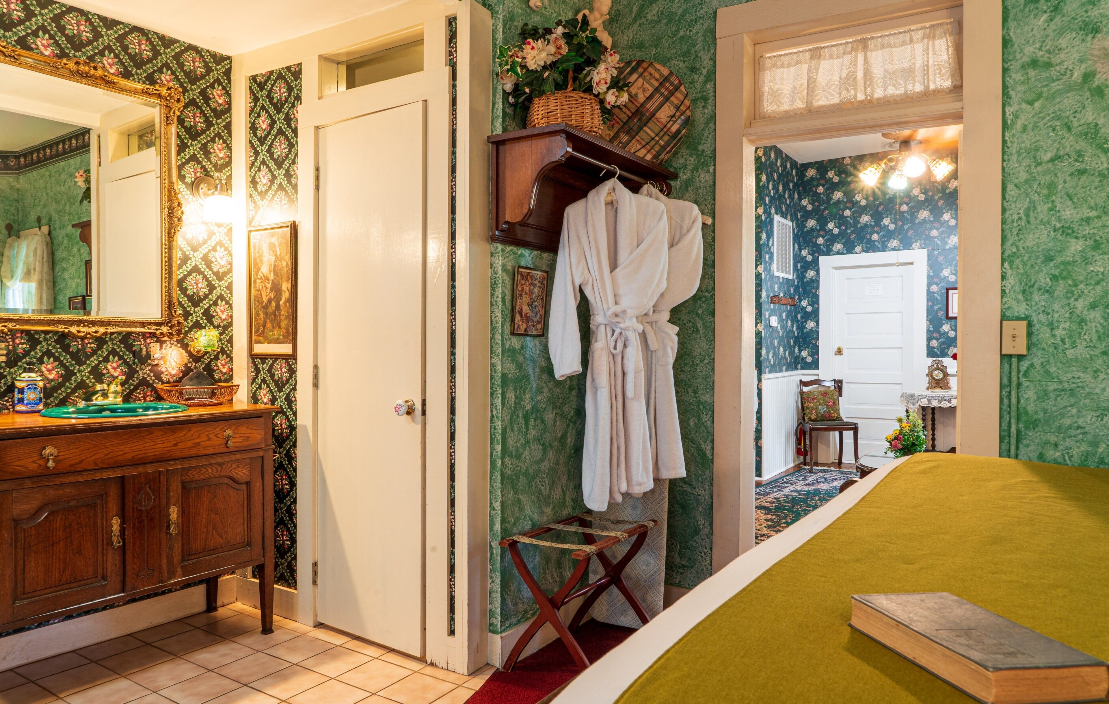 A room with a bed, a dresser, a mirror, and a door leading to another room.