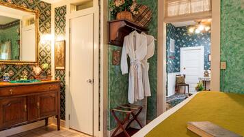 A room with a bed, a dresser, a mirror, and a door leading to another room.