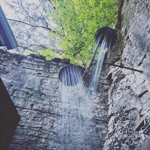 A waterfall feature with a rustic stone wall and a wooden structure. - Cliff Cottage Inn - Alfred Lord Tennyson King Jacuzzi Suite (Eureka Springs)