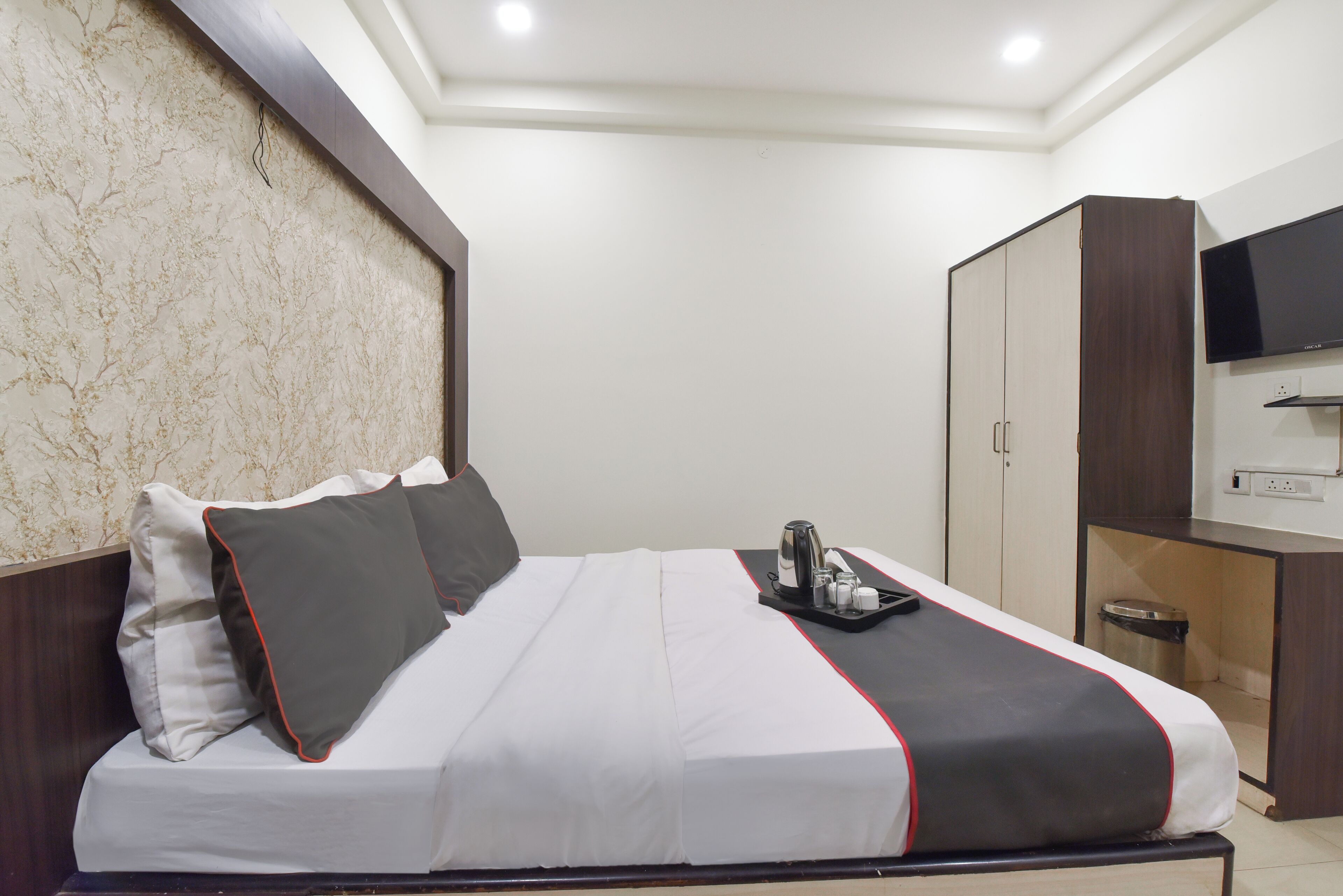 A hotel room with a bed, a television, a wardrobe, and a trash bin.