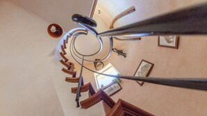 Una escalera de caracol con barandillas de metal y escalones de madera, que conduce a un piso superior.