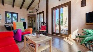 Un salón amplio con techo de madera, ventanas grandes y una variedad de muebles coloridos.