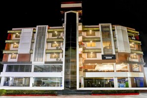 Un hotel de varios pisos con un atrio central, balcones y un letrero que indica que es una 'Townhouse & Contemporary Residence'.
