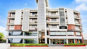A multi-story hotel with a central vertical feature, large windows, and a sign indicating 'Townhouse' accommodation. - Super Townhouse Prahladnagar (Ahmedabad)