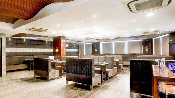 A modern restaurant interior with seating arrangements, tables, and a counter area. - Super Townhouse Prahladnagar (Ahmedabad)