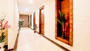 A hotel hallway with potted plants, wooden doors, and a tiled floor. - Super Townhouse Prahladnagar (Ahmedabad)