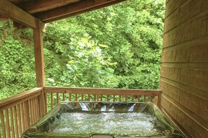 Ein Whirlpool auf einer Holzterrasse mit Blick auf dichtes Grün.