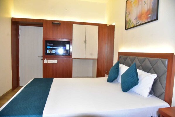 Une chambre d’hôtel avec un lit, une télévision, une armoire et un tableau au mur.