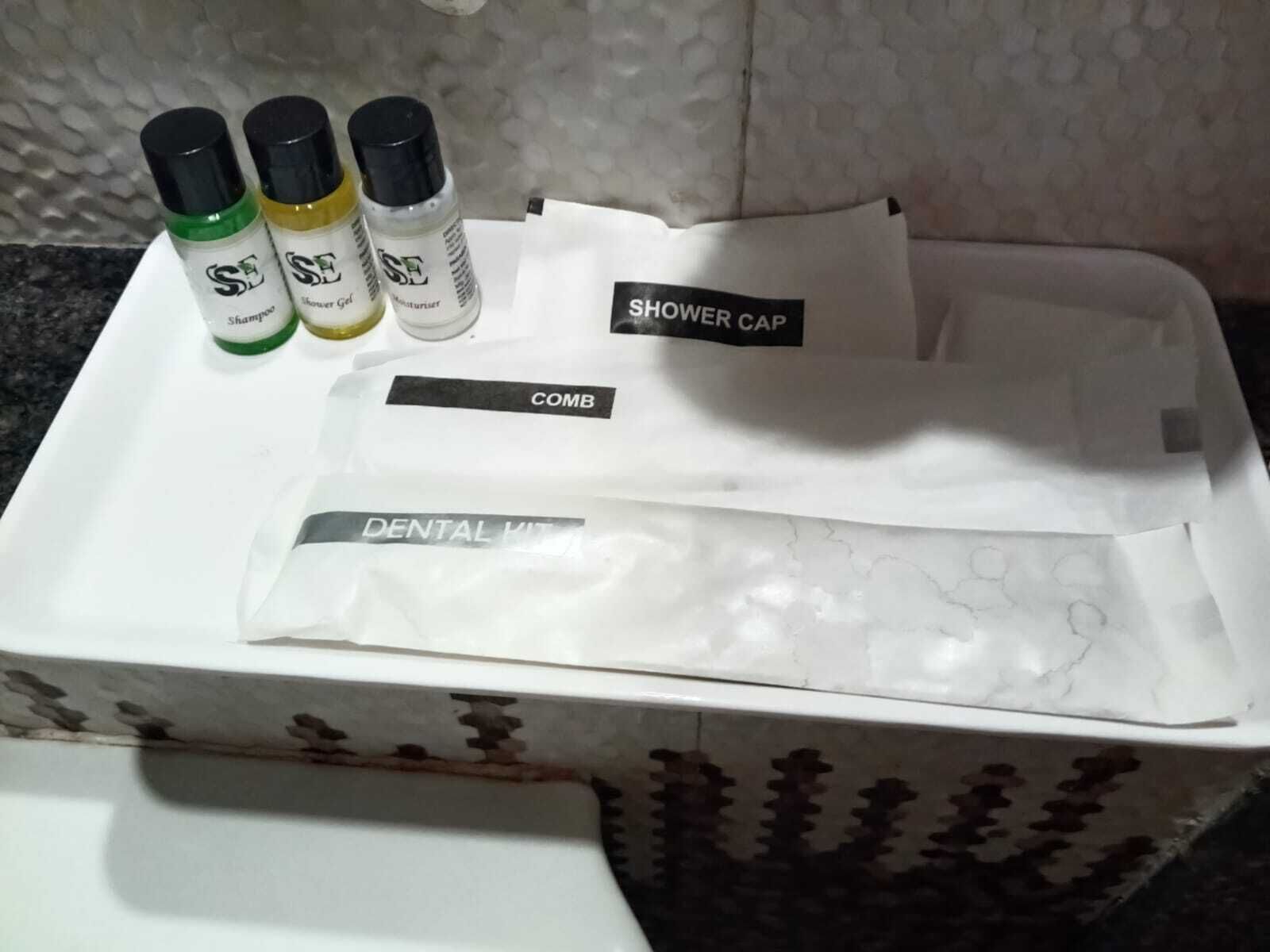A bathroom with a shower cap, comb, and three bottles of shampoo.