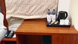 A hotel room with a wooden desk, a telephone, a tray with bottled water, a coffee maker, and two mugs. - HOTEL VEDIKA  (Ranchi)
