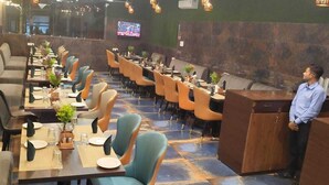 A restaurant with multiple dining tables, chairs, and a counter. - HOTEL VEDIKA  (Ranchi)