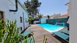 A swimming pool with a wooden deck, surrounded by white walls and potted plants. - "Villa of Arts".House with the pool, minutes from ocean and not far from Lisbon (Corroios)