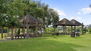 Ein Park mit hölzernen Lauben, Picknicktischen und einer Rasenfläche.