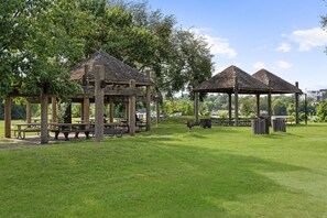 Een park met houten prieel, picknicktafels en een gazon.