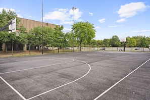 An outdoor basketball court with a fence, trees, and a building in the background. - 2BR 2BA DC Oasis Free Parking Near Capitol Hill (Washington)