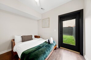 Een slaapkamer met een bed, een raam en een deur naar buiten.
