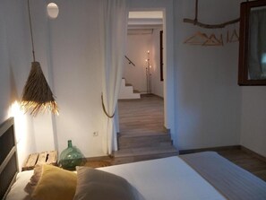 A bedroom with a bed, a hanging lamp, a green bottle, and a staircase leading to another room. - YourHouse Sa Casa apartment (Sineu)