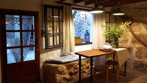 Ein rustikales Interieur mit einer Steinsitzbank, einem Holztisch und einem Fenster mit Vorhängen.
