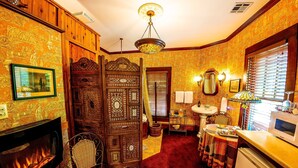 Une chambre traditionnelle dotée d’une cheminée, d’un coin repas et d’une cuisine équipée d’un four à micro-ondes.
