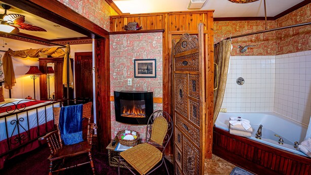 Une chambre de style traditionnel, dotée d’une cheminée, d’une baignoire et d’une chaise en bois.