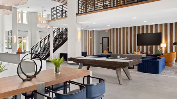 A modern hotel lobby with a pool table, seating area, and a staircase. - Riviere 2BR Apartment Pet Friendly Oasis Sleeps 6 Close to Epic Universe Pool & Gym (Orlando)