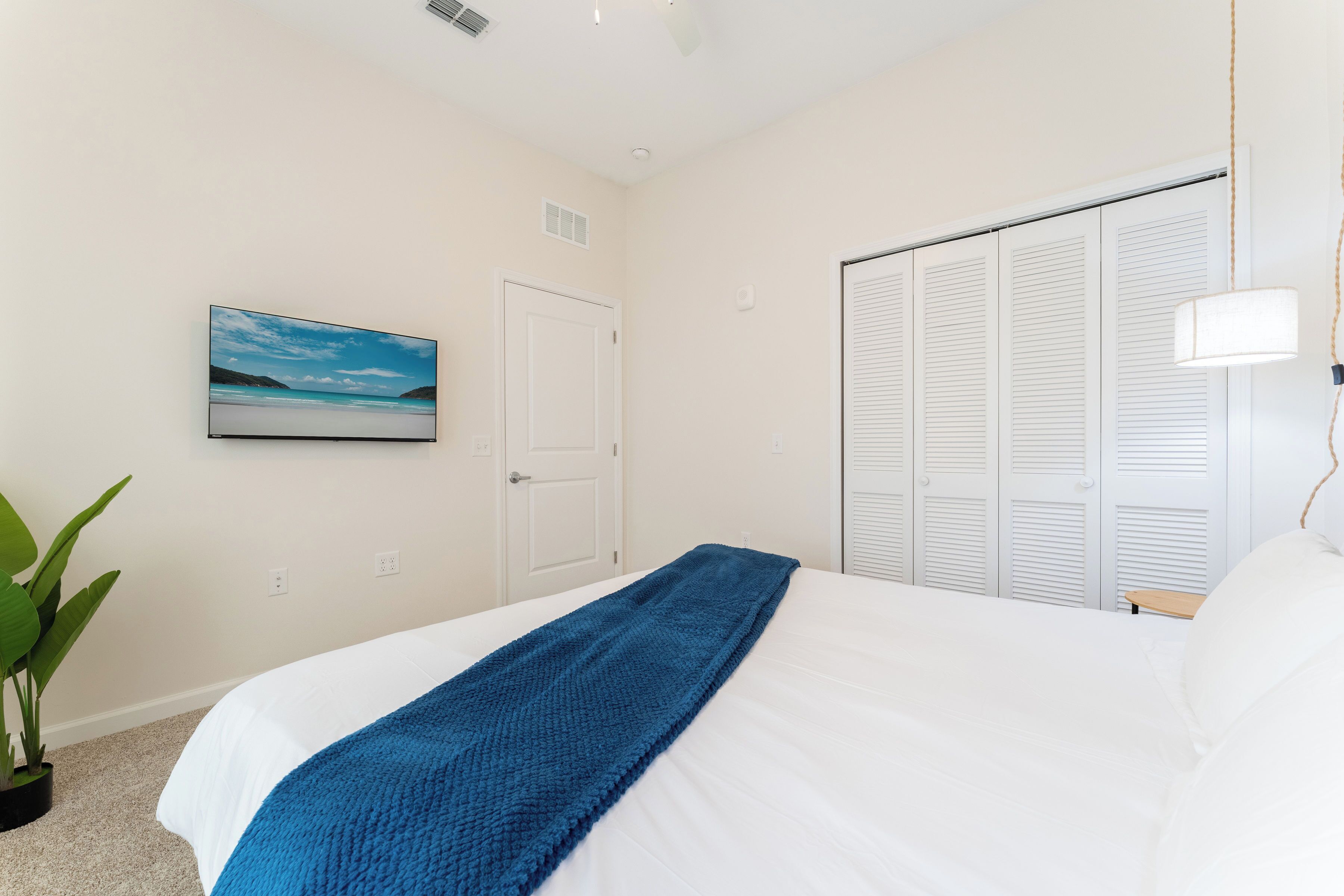 Une chambre à coucher avec un lit, un tableau, une armoire et une plante.