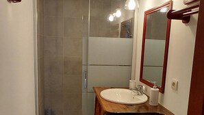 Une salle de bain équipée d’une douche, de toilettes, d’un lavabo et d’un miroir.