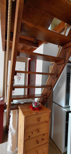 A wooden staircase with a rope, a wooden chest of drawers, and a refrigerator in the background. - Cocoon in quiet residence with private garden (Malissard)