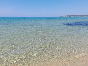 Clear shallow waters, a sandy beach, and distant rocky formations. - 700 m from the sea with a view of the largest sand dunes in Europe, sea view (Torre dei Corsari)