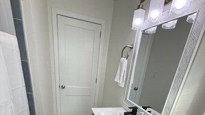 Ein Badezimmer mit Waschbecken, Holzschrank, großem Spiegel und Toilette.