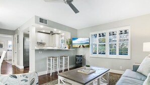 A modern living room with a sofa, coffee table, and a TV mounted on the wall. - Delray Breezes !NEW! WALK to BEACH & THE AVE! (Delray Beach)