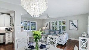 A modern living room with a dining area, a chandelier, and artwork on the walls. - Delray Breezes !NEW! WALK to BEACH & THE AVE! (Delray Beach)