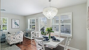 A dining area with a chandelier, white furniture, and a view through the window. - Delray Breezes !NEW! WALK to BEACH & THE AVE! (Delray Beach)