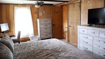 A bedroom with a bed, a dresser, a television, a ceiling fan, and wooden walls.