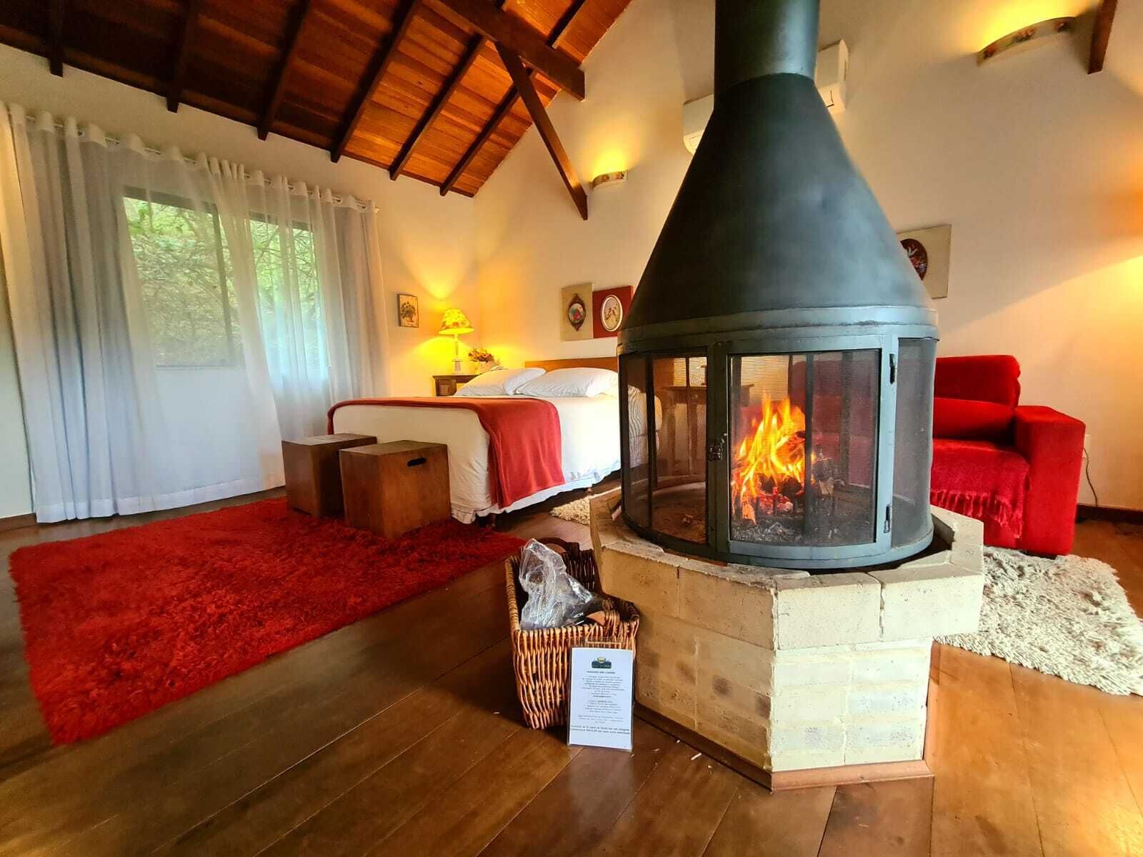 Una habitación acogedora con una cama, un sofá rojo, una chimenea y un techo de madera.