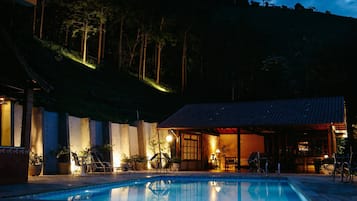 Una piscina al aire libre, sombrillas, sillones reclinables de piscina
