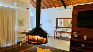 Una sala de estar con chimenea, un sofá, un televisor y techo de madera.