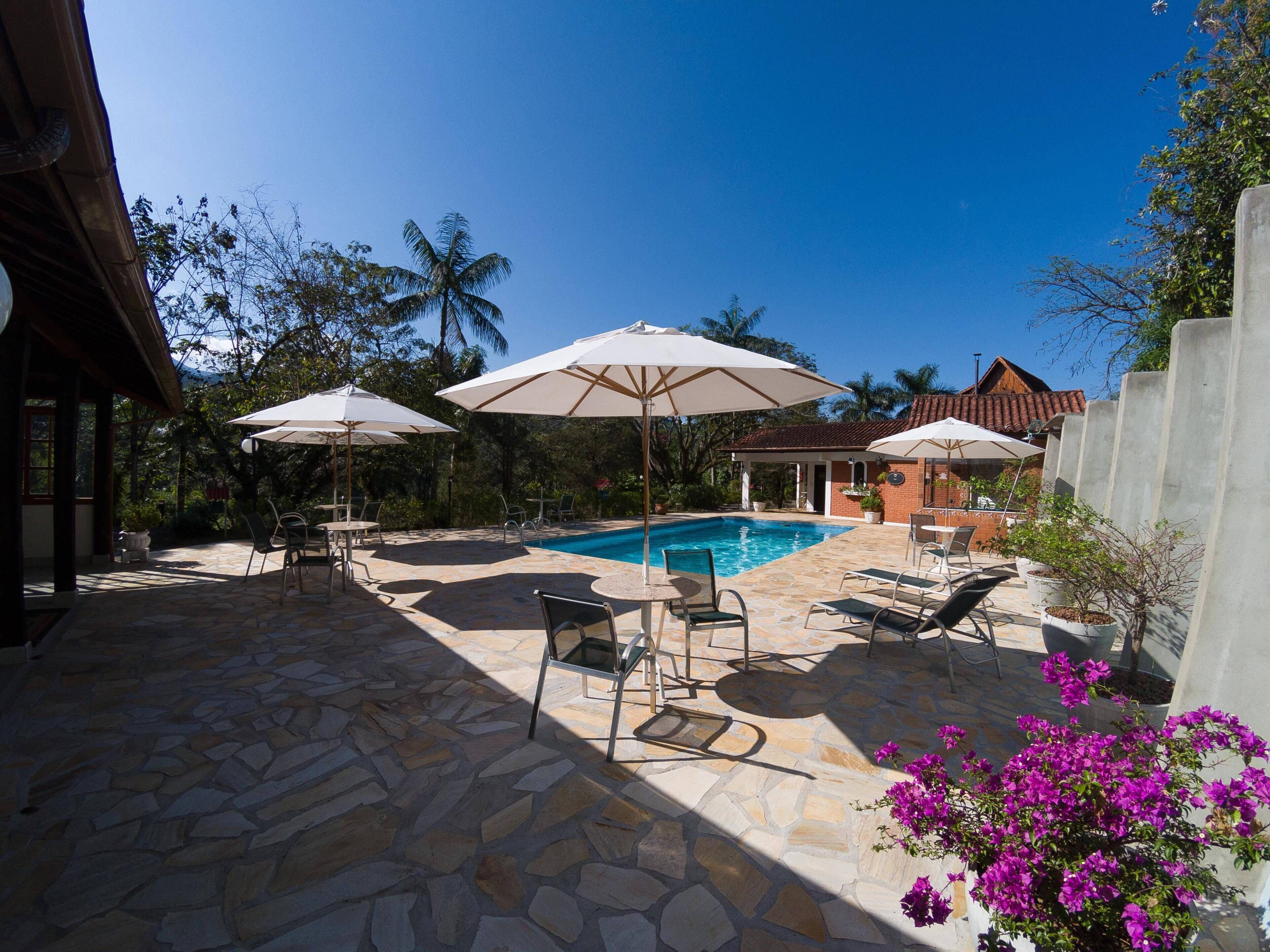 Una piscina al aire libre, sombrillas, sillones reclinables de piscina