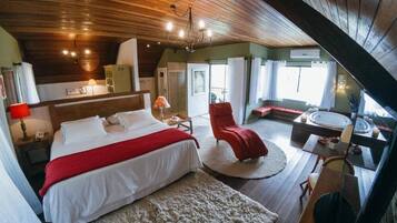 Un dormitorio con una cama, una silla roja, una mesa redonda y vistas al exterior.