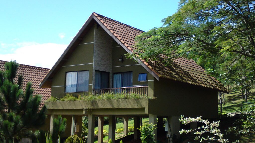 A two-story house with a balcony, a tiled roof, and a garden area.