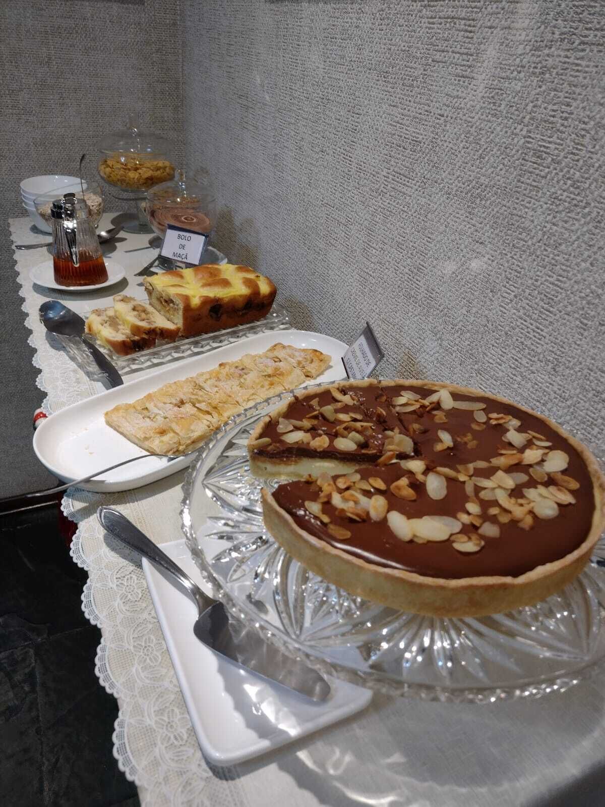 Een buffettafel met diverse desserts, waaronder een chocoladetaart met amandelen, een stukje taart en andere gebakjes.