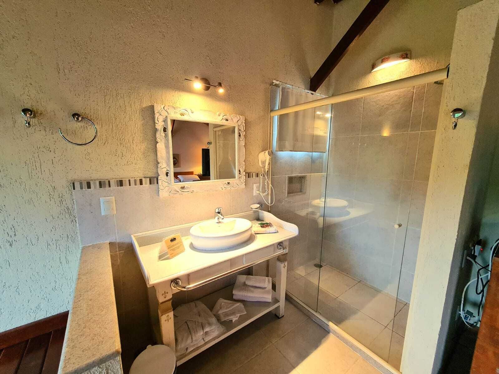 A bathroom with a round sink, a mirror, a towel rack, and a glass shower enclosure.