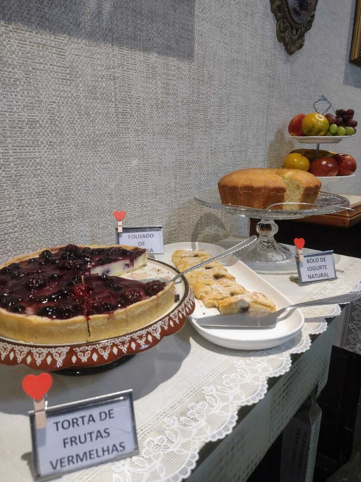 A dessert display with a berry tart, a slice of pie, a fruit bowl, and a cake.