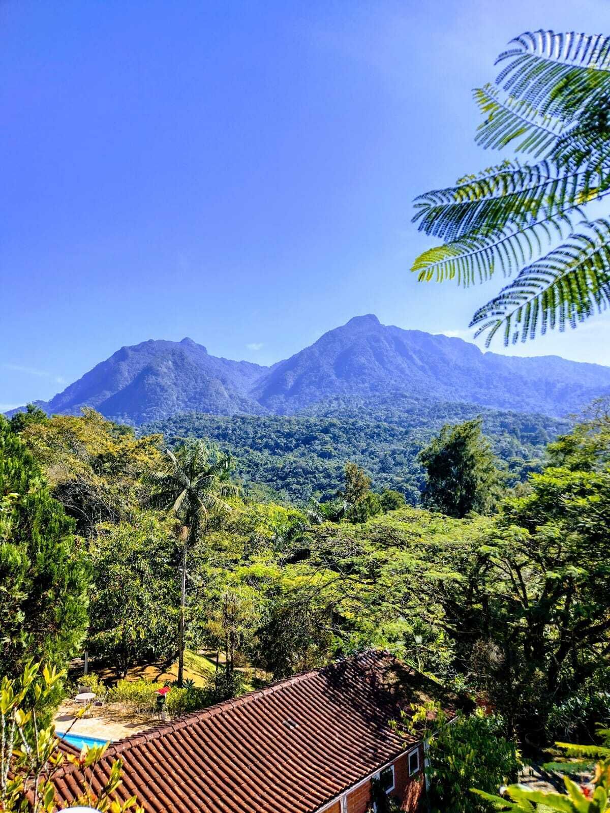 Paisaje montañoso con una casa que tiene techo de tejas y una piscina.