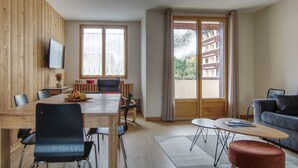 Una sala de estar moderna con comedor, ventanas amplias y vista a un edificio.